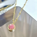 Close-up of pink faceted gemstone pendant with gold twist border on beaded necklace - Rhodonite