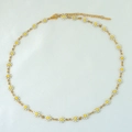 Close-up of titanium gold chain necklace featuring white and yellow enamel daisy charms - White Necklace