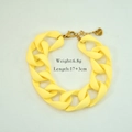 Detail eines gelben Acryl-Gliederarmbands mit goldenem Karabiner und Herz-Anhänger - Gelb