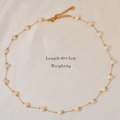 Detail view of pearl and amber bead necklace with lobster clasp on silk background - Satellite Chain
