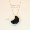 Macro detail of moon-shaped black stone pendant on gold stainless steel chain - Black Agate