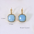 Détail de boucles d'oreilles carrées en pierre bleu clair avec monture dorée élégante - Amazonite