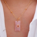 Dettaglio di una collana con pendente in pietra naturale rosa e finiture in oro su modella - Quarzo rosa