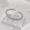 Detail of silver woven titanium steel cuff bracelet on a white minimalist stone base - Woven Cable Style (B713 Silver)