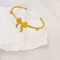 Elegant gold bow open bangle with white pearls on a minimalist stone background - Pearl Bow Knot Style (B765) / Gold