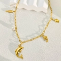 Detailed macro view of 18k gold plated ocean charms and white pearl on necklace - Dolphin