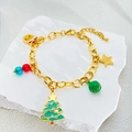 Detailopname van gouden kerstarmband met bedeltjes van de kerstman op een stenen plateau - Kerstboom Armband