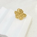 Detailed close-up of a large gold flower ring with hammered texture on white platform - Flower Style