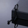 Close-up of matte black punk earrings with dangling chains and pointed spike charms - Piercing Style / Black Rivet Dangle
