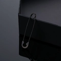 Macro shot of minimalist matte black stainless steel safety pin earrings with reflection - Black