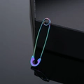 Rainbow gradient safety pin earring in polished stainless steel on a dark reflective surface - Colorful