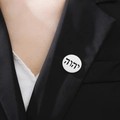 Silver round brooch with Hebrew text design pinned to a black suit lapel - Steel Hebrew YHWH
