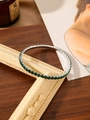 Detailed macro view of square-cut emerald green zircons on a silver-tone tennis bracelet - Green