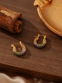 Vista macro de pendientes huggie dorados con circonitas de colores sobre fondo madera - ZHE979 multicolor