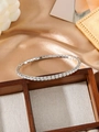 Detailed macro view of a silver tennis bracelet with square-cut cubic zirconia on satin - White