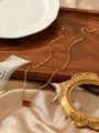 Dettaglio della collana a catena dorata con un ciondolo rettangolare in zircone rosso - Rosso