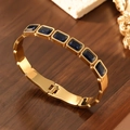 Close-up of gold-plated bangle with blue square gemstones and spring clasp design - 18K Gold / Blue