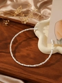 Detail view of gold-plated bamboo choker with white enamel segments on a silk background - White