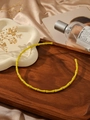 Detailed close-up of yellow bamboo joint necklace on a wooden tray with a minimalist style - Yellow