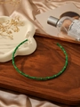 Detailed view of a green enamel bamboo-style gold-plated stainless steel headband on a tray - Green