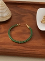 Detalle de pulsera tennis bañada en oro 18k con cristales verdes sobre fondo de madera - Diamante de Imitación Verde (ZHB712)