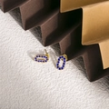 Dettaglio di orecchini ovali placcati in oro con zirconi blu scuro su uno sfondo - Zirconia Blu Scuro (ZHE1981)