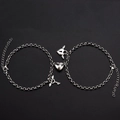 Macro shot of stainless steel couple bracelets with magnetic hearts and winged lock charms - Heart Key Bracelet A