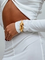 Gros plan d'un large bracelet manchette doré sculptural sur une manche de chemise blanche - Style de Vague Irrégulière / Or