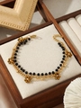 Dettaglio del bracciale dorato multistrato con perline nere e ciondolo a fiore in mostra - Stile Perline Sfaccettate Nere (ZHB47) / Oro