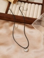 Detailed view of silver heart pendant with black leather cord on champagne silk fabric - Polished Steel Heart Style (ZHN331 Steel)