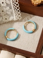 Detailopname van gouden roestvrijstalen oorringen met lichtblauw email op houten blad - Emaille Ring (ZHE322) / Dunne ring / Blauw