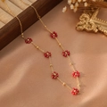Vista dettagliata dei ciondoli a fiore con perline rosse su catena dorata in acciaio inox - Stile con Perline Rosse (ZHN2325 Oro)