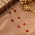 Gros plan d'un collier en or avec fleurs rouges à cinq pétales sur satin champagne - Style Rouge (ZHN2318 Or)