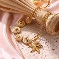 Meeresstil Muschelarmband mit goldenem Seestern und Perle auf rosa Seide Hintergrund - Seestern Muschel Halskette / Gold Halskette