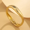 Dettaglio del bracciale rigido dorato in acciaio lucido con chiusura a cerniera - Gioielli a cerniera con linea fluida lucida / Oro 18K