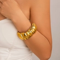 Dettaglio di un bracciale a fascia larga in acciaio inossidabile dorato con trama a onde - Stile texture a onde / Oro 18K