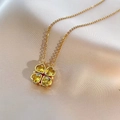 Detailed view of a gold clover necklace with four yellow heart-shaped crystals on silk fabric - Yellow Heart Necklace