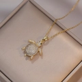 Detail of a gold turtle pendant with sparkling cubic zirconia on a jewelry box - Turtle Necklace / Gold
