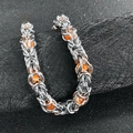 Macro shot of silver Byzantine chain bracelet with orange beads on black texture - Orange