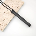 Detalle del colgante de meditación cilíndrico negro sobre fondo de piedra texturizada - Tubo Roscado / Negro