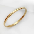 Detalle macro del anillo de acero inoxidable dorado pulido con acabado espejo - Bangle liso / Dorado