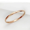 Primer plano de una pulsera minimalista de acero inoxidable oro rosa con acabado espejo pulido - Bangle liso / Rosa oro