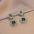 Macro detail of silver floral earrings with emerald green zircon and colorful accents - Steel Emerald Earrings