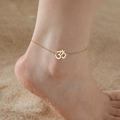 Double layer gold stainless steel Yoga Om charm anklet shown on beach sand background - Cable Chain / Gold