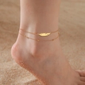 Double-layered gold stainless steel anklet featuring a feather charm on sandy beach - Gold-Double Layer