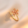 Eleganter vergoldeter Titanring mit orangefarbenen Zirkonia-Blüten auf Satin-Hintergrund - J0244