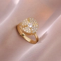 Drehbarer Goldring mit funkelndem Zirkonia auf champagnerfarbenem Seidenhintergrund - Goldener rotierender Blumenring