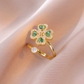 Detailansicht eines goldenen Kleeblatt-Rings mit grünen Zirkonsteinen auf rosa Seide - Grüner Vierblättriger Kleeblatt Offener Ring (J0323)