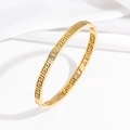 Vintage golden stainless steel bangle with Greek meander cutout on white satin cloth - Meander Pattern Gold Style (TT0098)