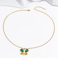Detailed close-up of emerald green butterfly necklace with gold chain on white silk - Necklace / Emerald